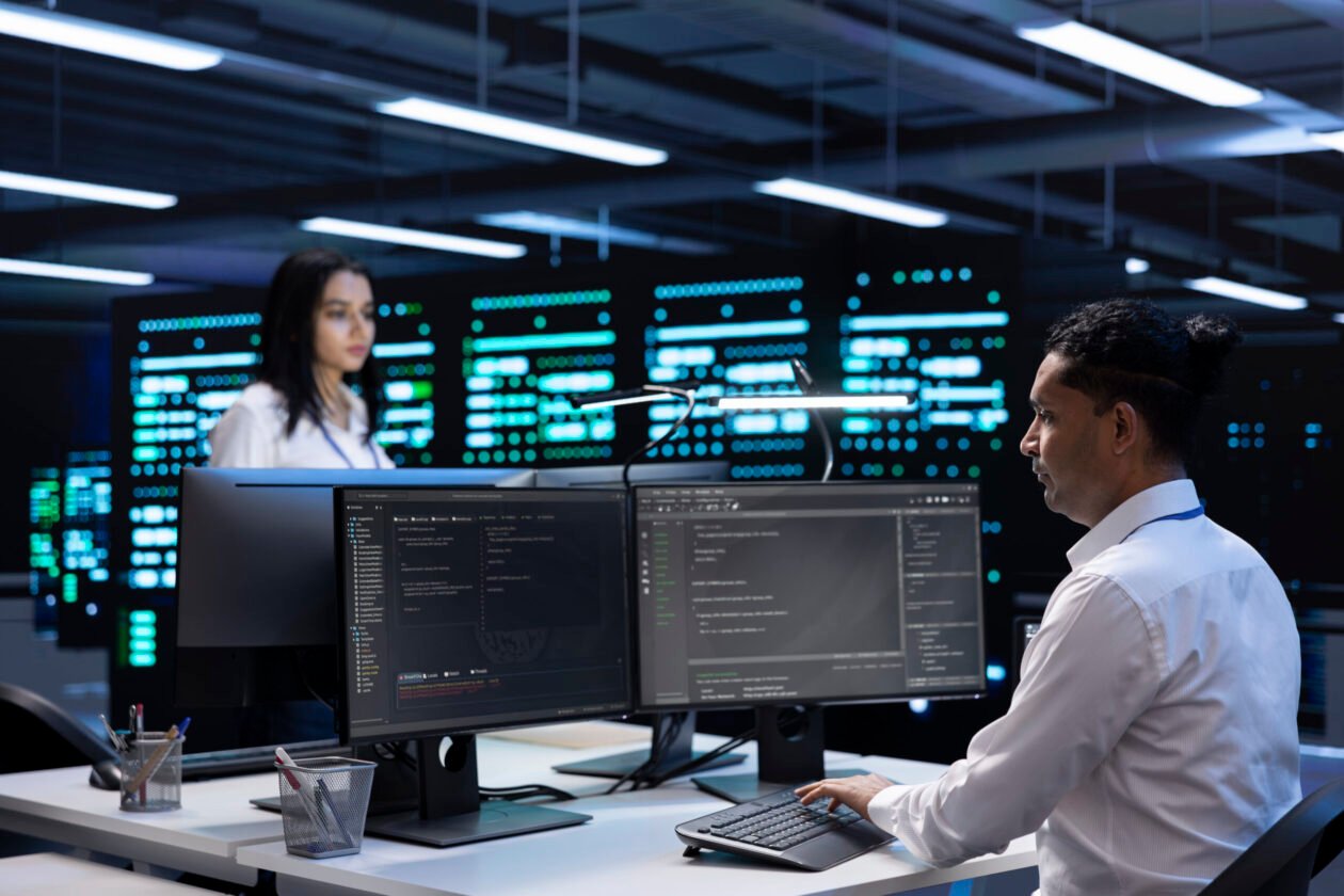 VMware & Hyper-V Services 1 Coworkers in data center using computers to find firewall misconfigurations